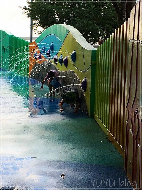 壁から水が噴水のように出ていて子供達が遊ぶ様子