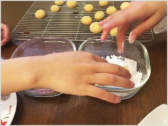 クッキーに粉砂糖をまぶす子供たち