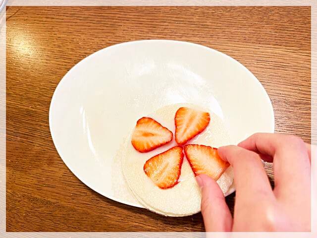 「ミルクせんべい」のイチゴを使ったアレンジでせんべいの上にイチゴをのせているところ